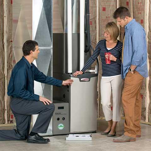 technician showing new furnace install to homeowners