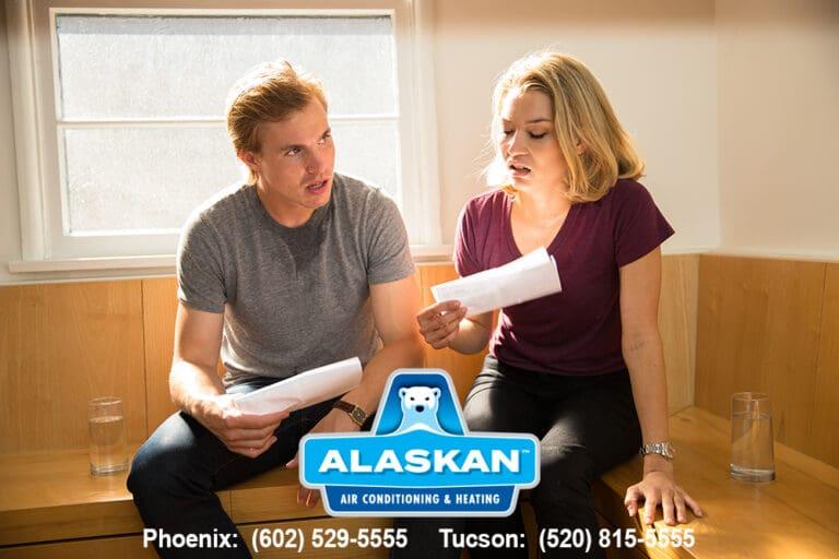 Two people sitting next to each other looking at paperwork, appear unhappy
