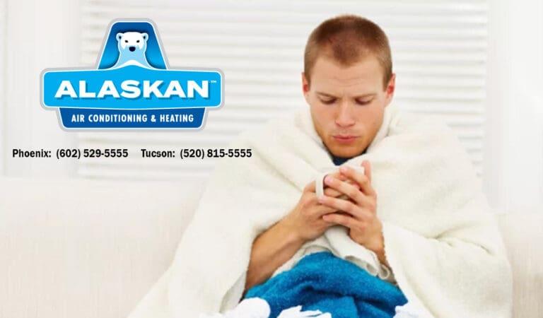 Man in blanket with cup in hands, looking into cup, with Alaskan Air Conditioning and Heating logo and contact phone numbers