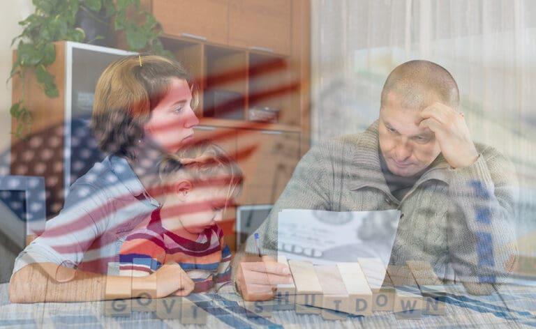 Family looking sad at table with paperwork with transparent overlays of american flag, dollar bill, and blocks spelling "govt shutdown"