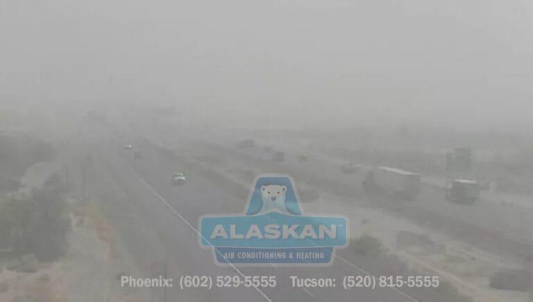 hard to see image of highway with traffic in dust storm with Alaskan Air Conditioning and Heating logo and contact phone numbers in bottom section