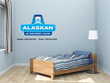 small bedroom with lamp and twin bed with Alaskan Air Conditioning and Heating logo and contact phone numbers in top left quadrant