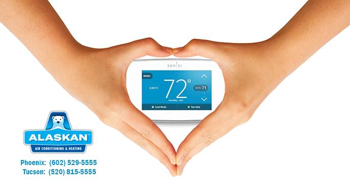 hands coming down over thermostat to make hands into heart around thermostat, Alaskan Air Conditioning and Heating logo and contact phone numbers in bottom left corner