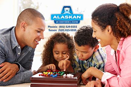 Family playing chinese checkers together with Alaskan Air Conditioning and Heating logo and contact phone numbers across top middle