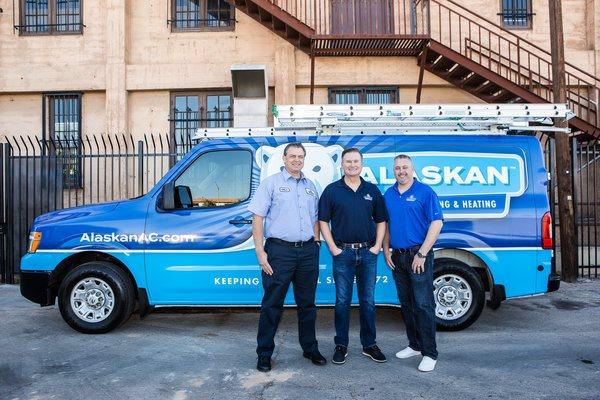 Three Alaskan techs standing in front of Alaskan AC branded van near building in parking lot